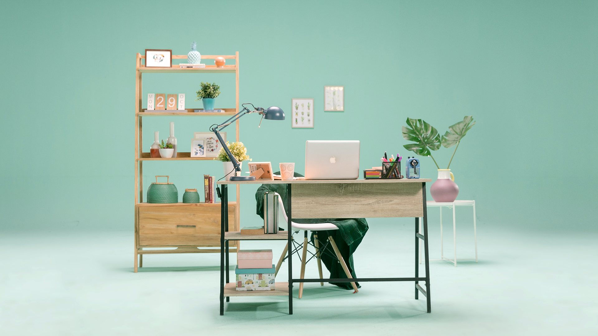 A mint green room decorated with a desk and shelves. A laptop sits on the desk.
